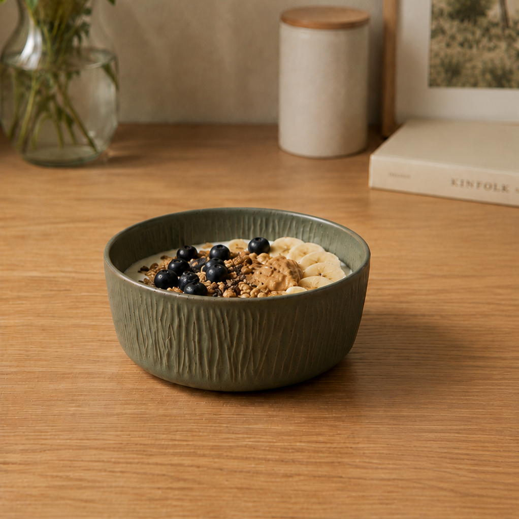 Deep Olive stoneware bowl with yogurt, granola, blueberries and banana on a wooden tabl