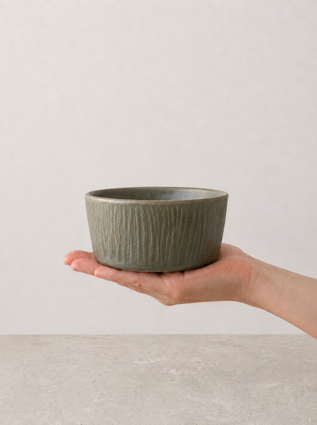 Deep Olive stoneware bowl by SOLI CERAMICS held in hand against a neutral background