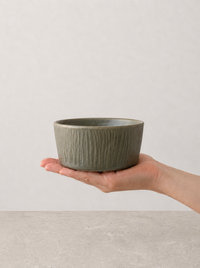 Deep Olive stoneware bowl by SOLI CERAMICS held in hand against a neutral background
