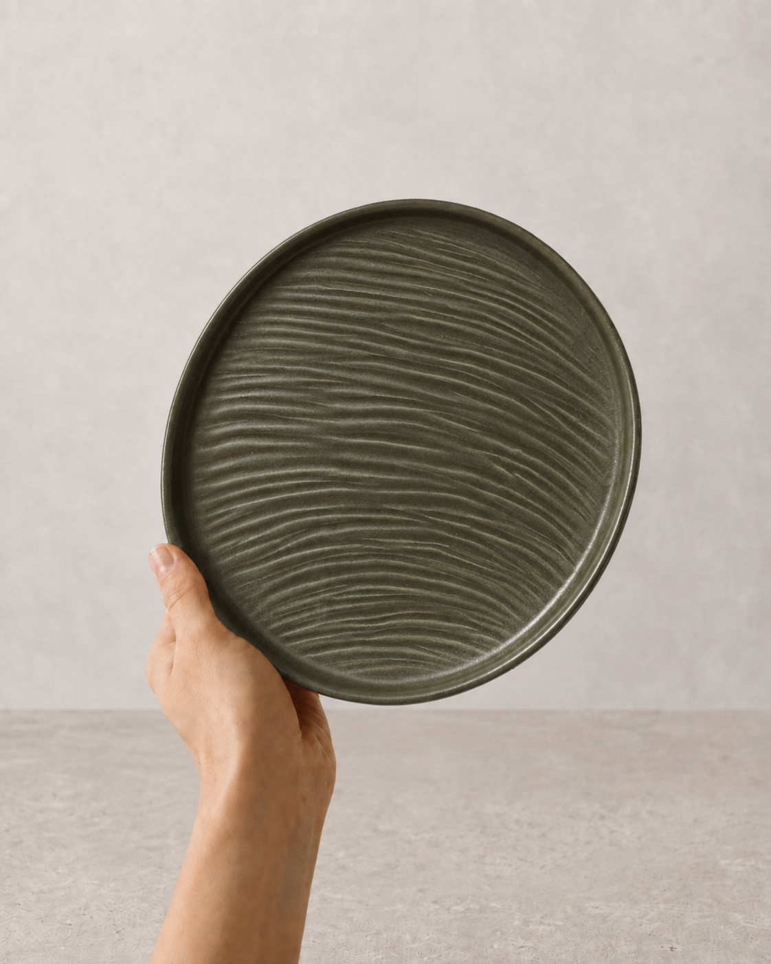 Deep Olive stoneware ceramic plate held in hand against a neutral background