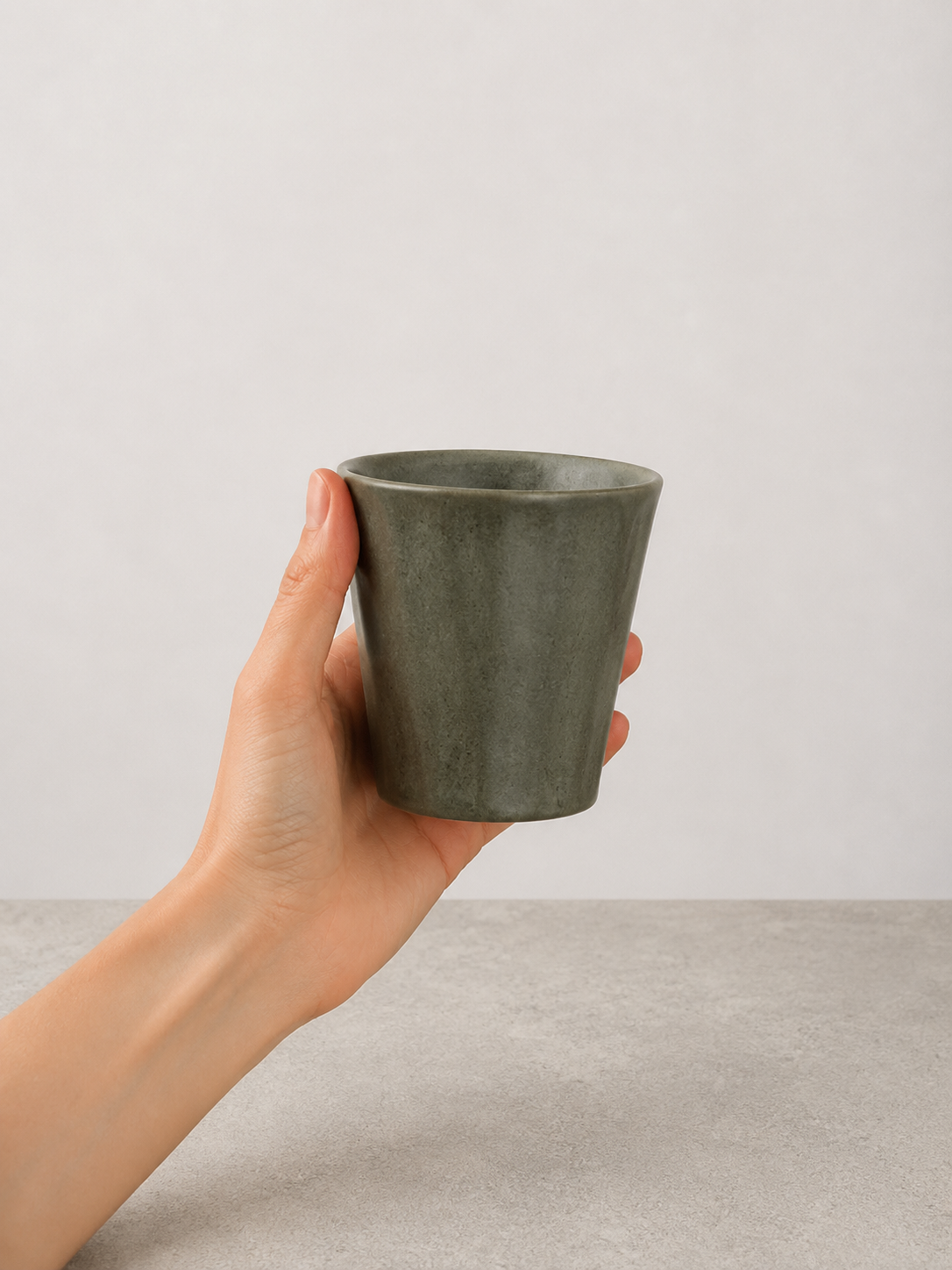 Deep Olive stoneware mug by SOLI CERAMICS held in hand against a neutral background