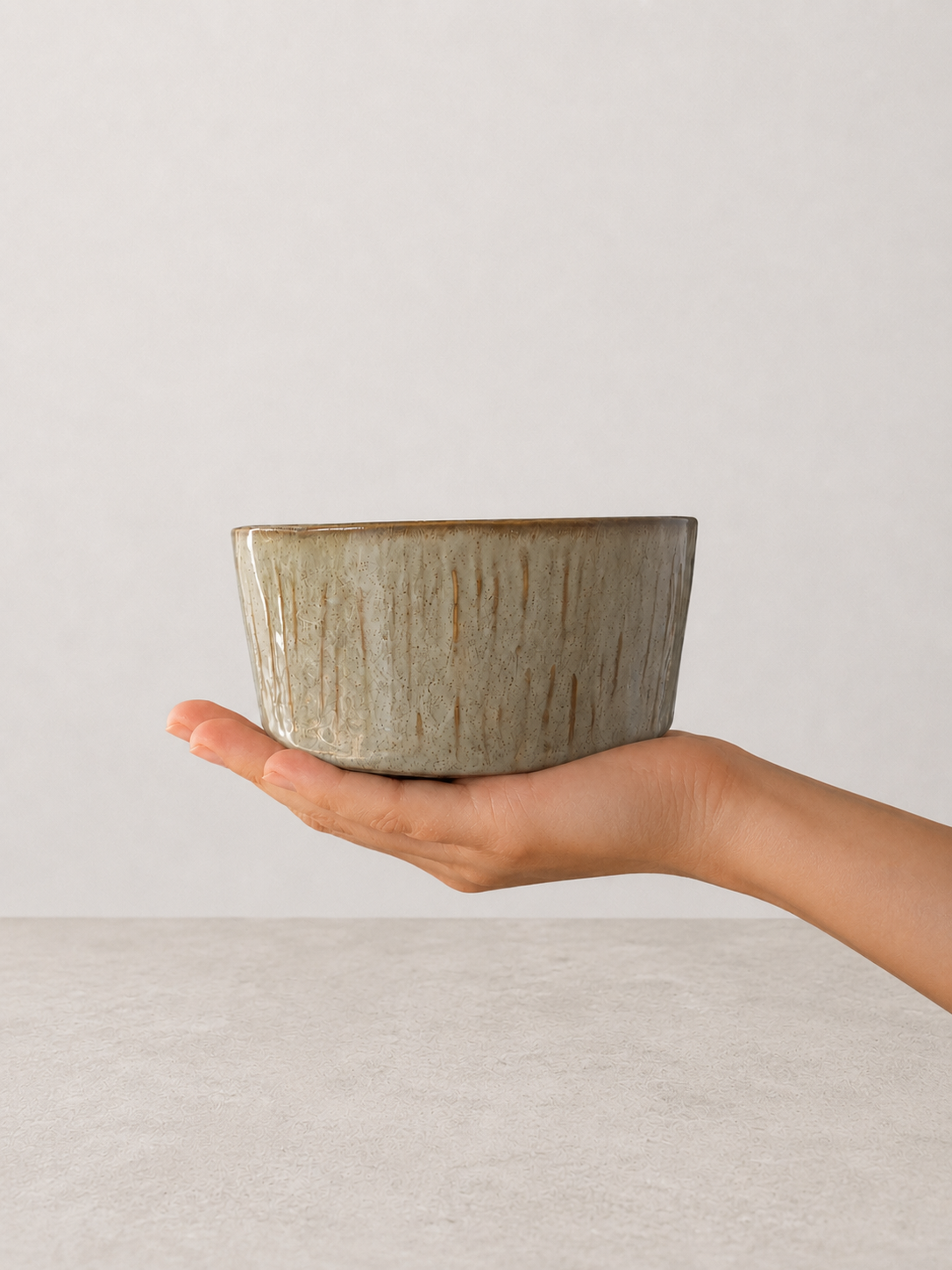 Sage Taupe stoneware bowl by SOLI CERAMICS held in hand against a neutral background